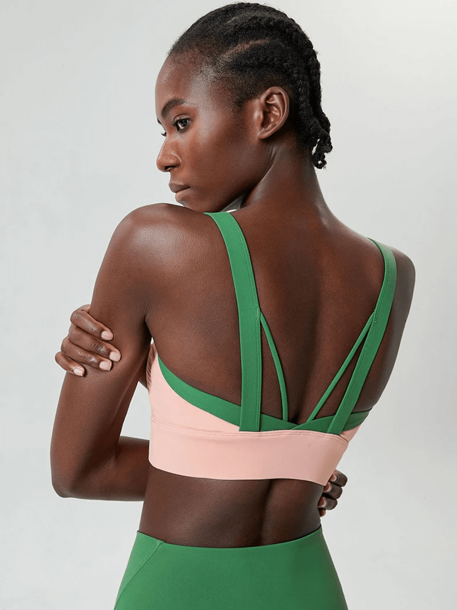 Woman wearing a two-color athletic sports bra top, showcasing a unique back design for yoga or fitness activities.